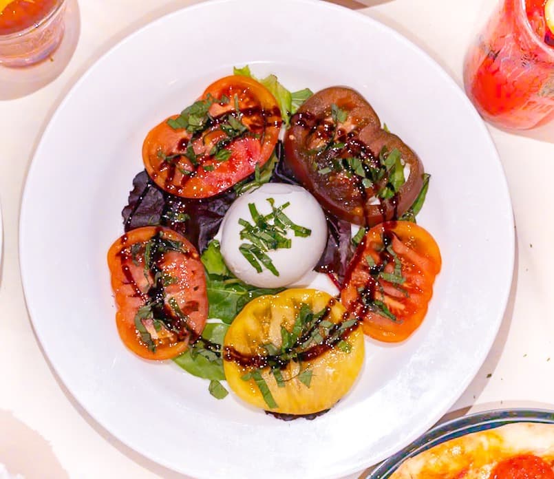 Caprese with heirloom tomatoes and creamy burrata, drizzled with balsamic glaze at MiraMare Ristorante